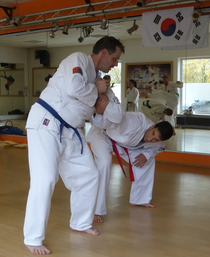 Zwei Trainierende üben in der Halle, wie man sich aus einem Griff löst, an der Wand die koreanische Flagge